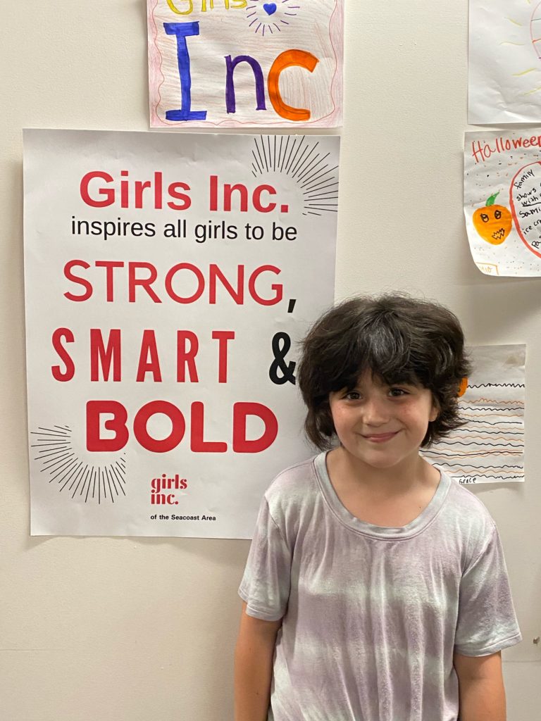 Young girl stands in front of post that says Strong, Smart & Bold