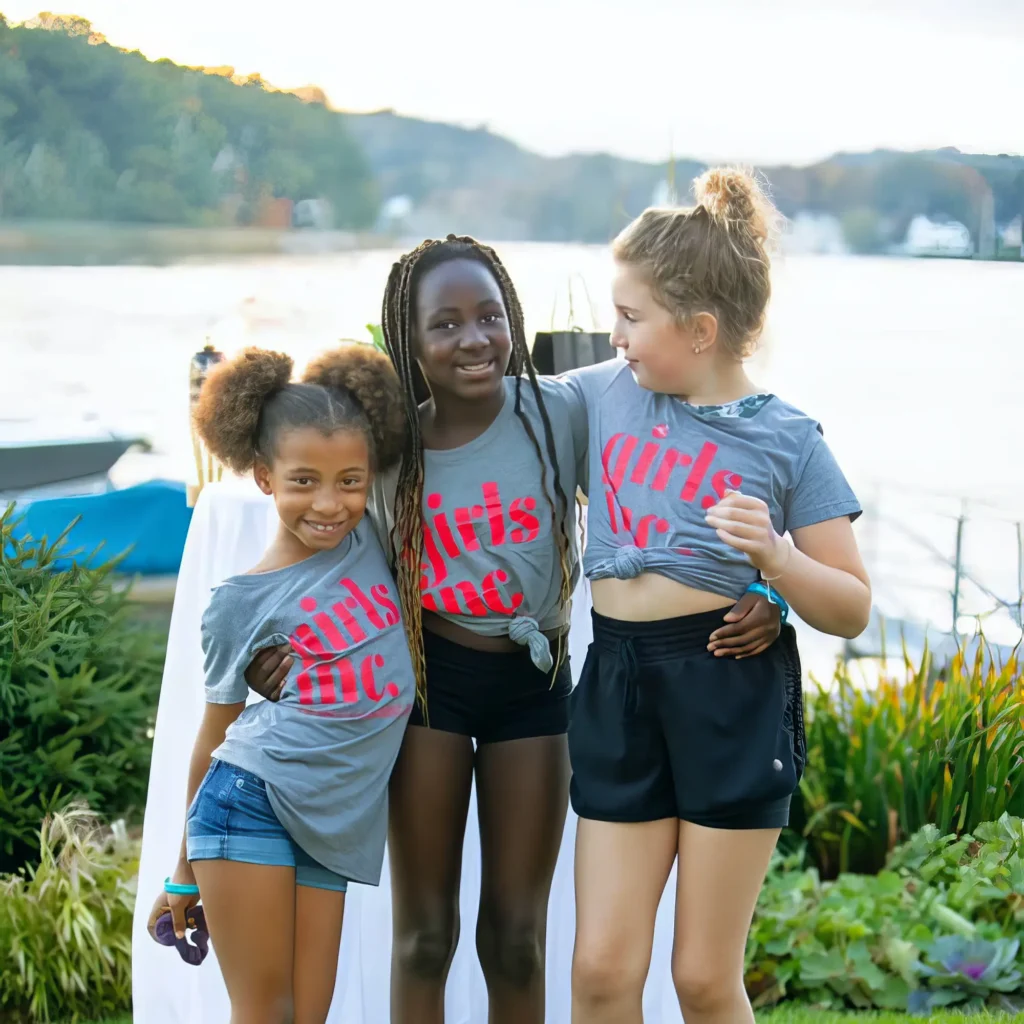 Three girls smiling with arms around each other